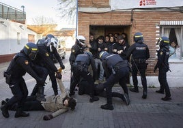 La Policía Nacional desaloja el acceso de la vivienda desahuciada ante la atenta mirada desde la ventana de Verónica, con su hijo en brazos.