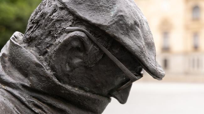 Qué lleva en las manos la estatua de Miguel Delibes ubicada en la Plaza de Zorrilla junto al Campo Grande?