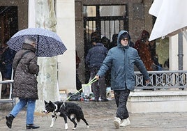 Capuchas y paraguas en la Plaza Mayor bajo los copos de nieve.