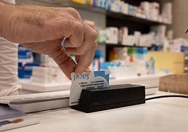 Un farmacéutico dispensa unos medicamentos mediante receta electrónica tras restablecerse el sistema.
