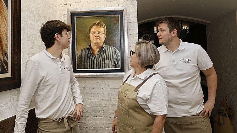 María José Amor y sus hijos Javier y Alejandro observan el cuadro con la imagen de Antonio Diez.