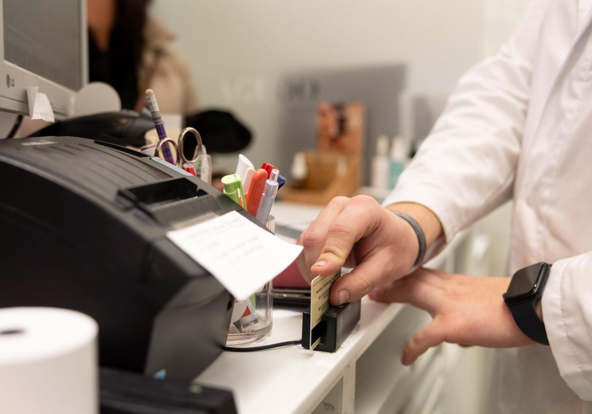 Un farmacéutico pasa la tarjeta de Sacyl por el lector.