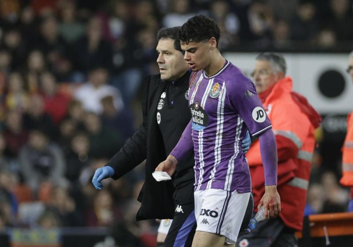 David Torres sale del terreno de juego acompañado del doctor López Moreno tras recibir un golpe de Sadiq durante el último Valencia-Real Valladolid