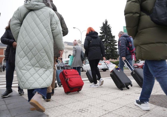 Varias personas con maletas, camino de la estación de ferrocarril.