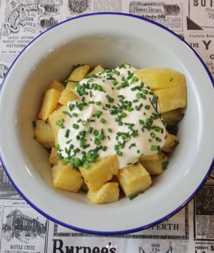 Imagen secundaria 2 - En el centro, Fernando de la calle junto a Felipe García y su hijo Juan García. Y algunos de los platos favoritos del Gastrobar Descosidos de Fernando de la Calle: ensaladilla tartufo y patatas con salsa.