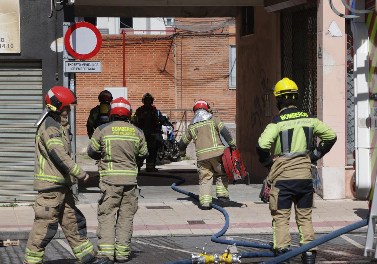 Imagen principal - Bomberos que acudieron al aviso del incendio y vecinos que siguen la intervención.