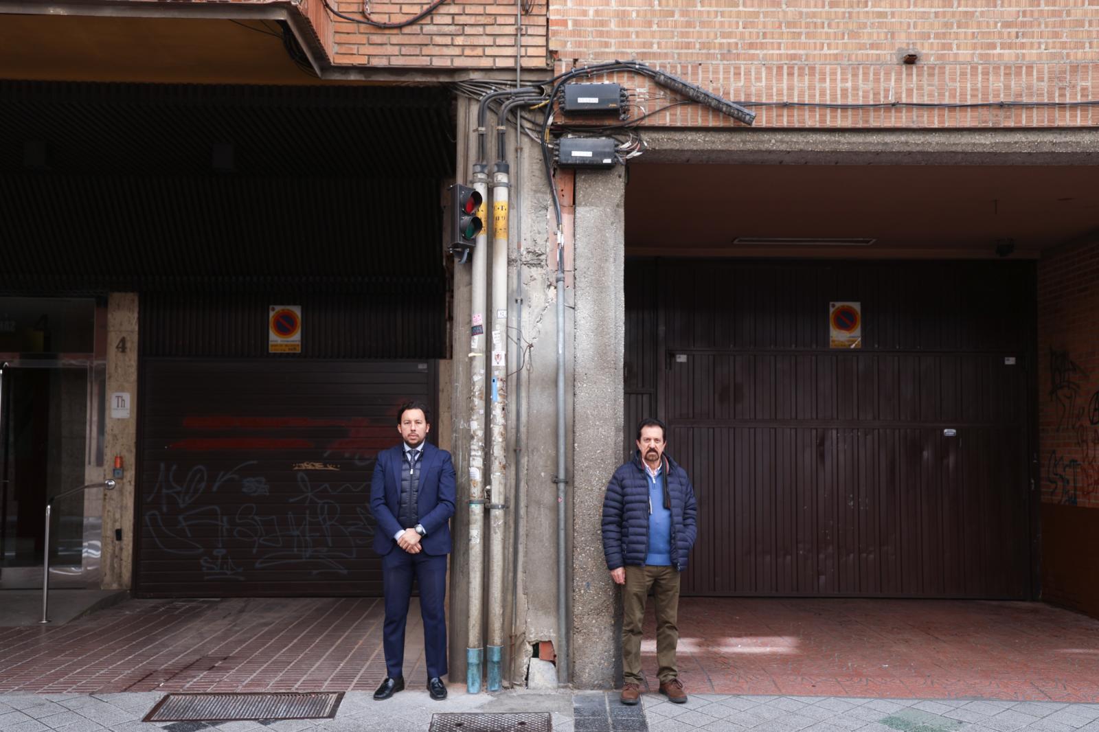 Alfonso Vela y José Fernando, vecinos de ambos portales, posan junto al muro cuyo derribo van a costear ambas comunidades.