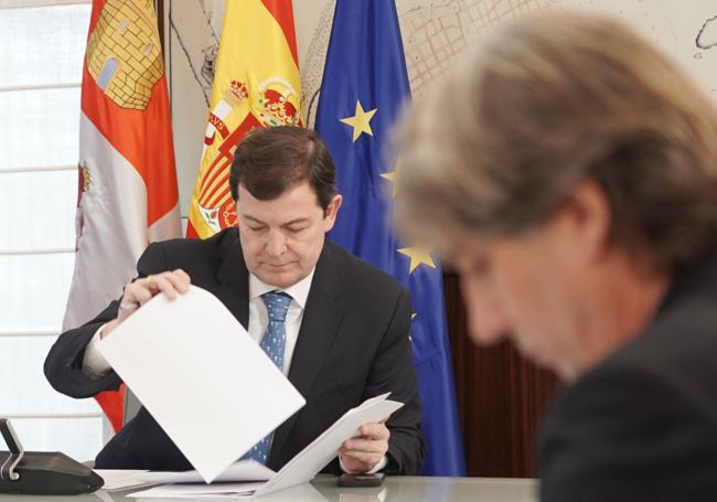 Alfonso Fernández Mañueco consulta unos papeles, con Carlos Martínez (PSOE) en primer término.