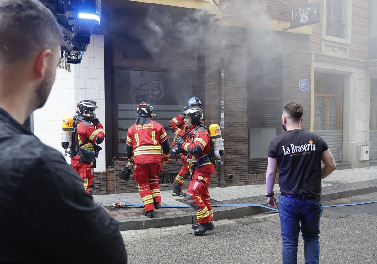 Los bomberos se adrentan en el restaurante, ante la mirada de los empleados.