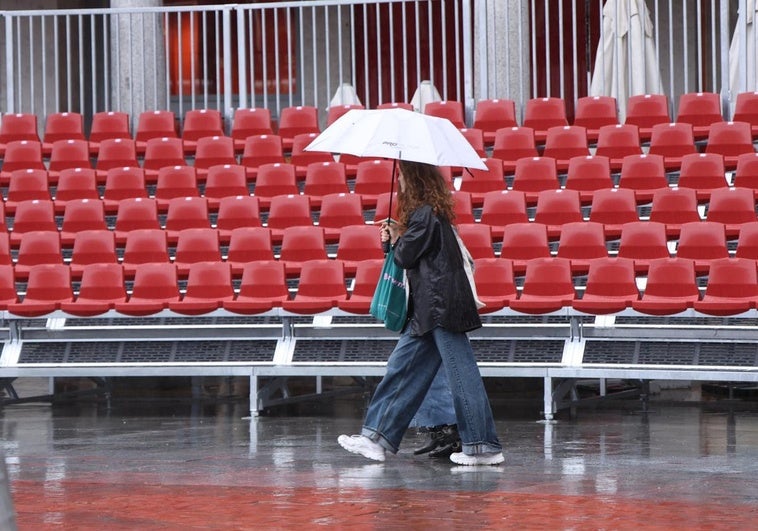Las gradas, vacías mientras los transeúntes se refugian de la lluvia con sus paraguas