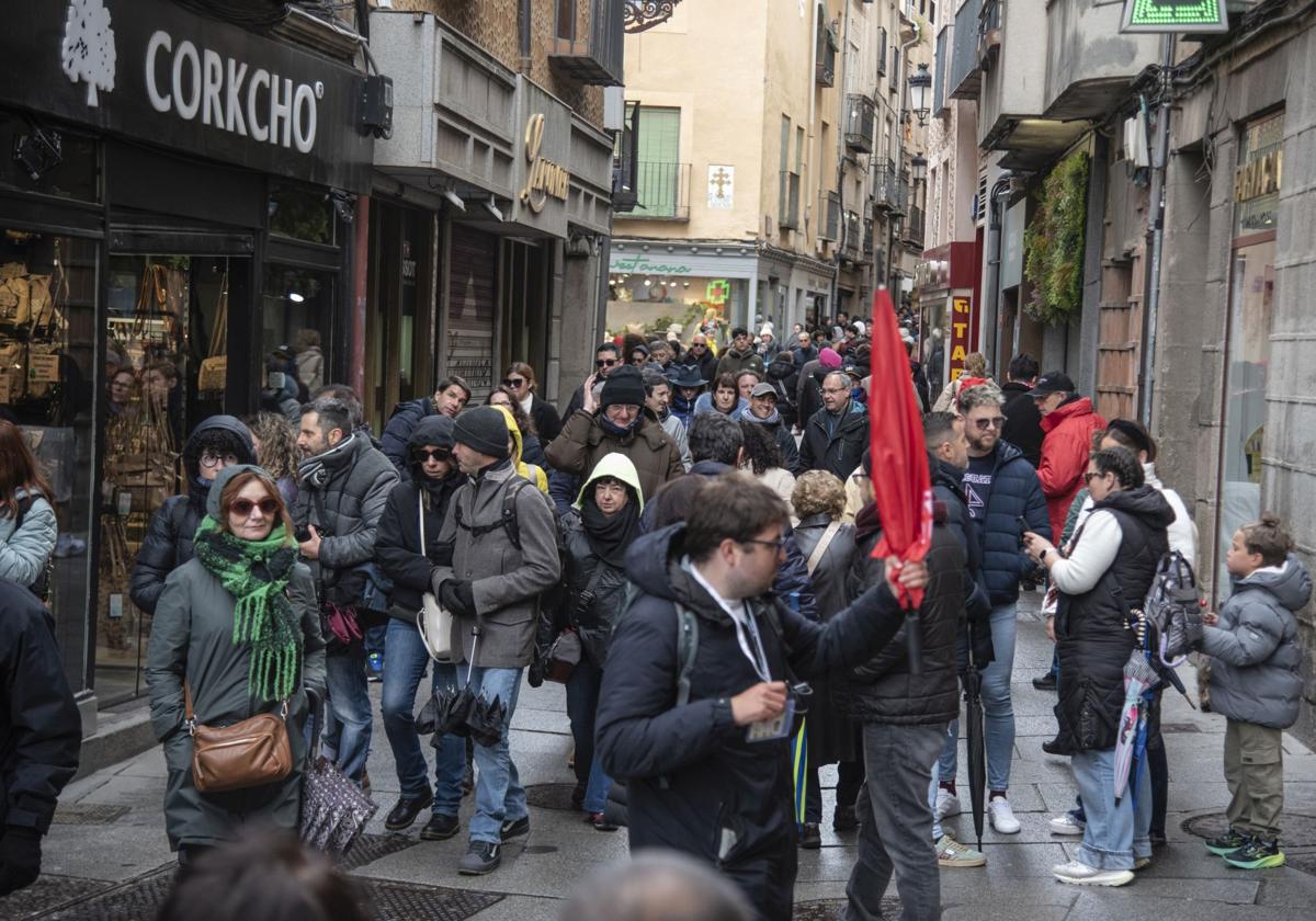 Grupos de turistas circulan por la Calle Real de Segovia este sábado lluvioso y ventoso.