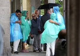 Turistas con chubasqueros, este viernes en Segovia.