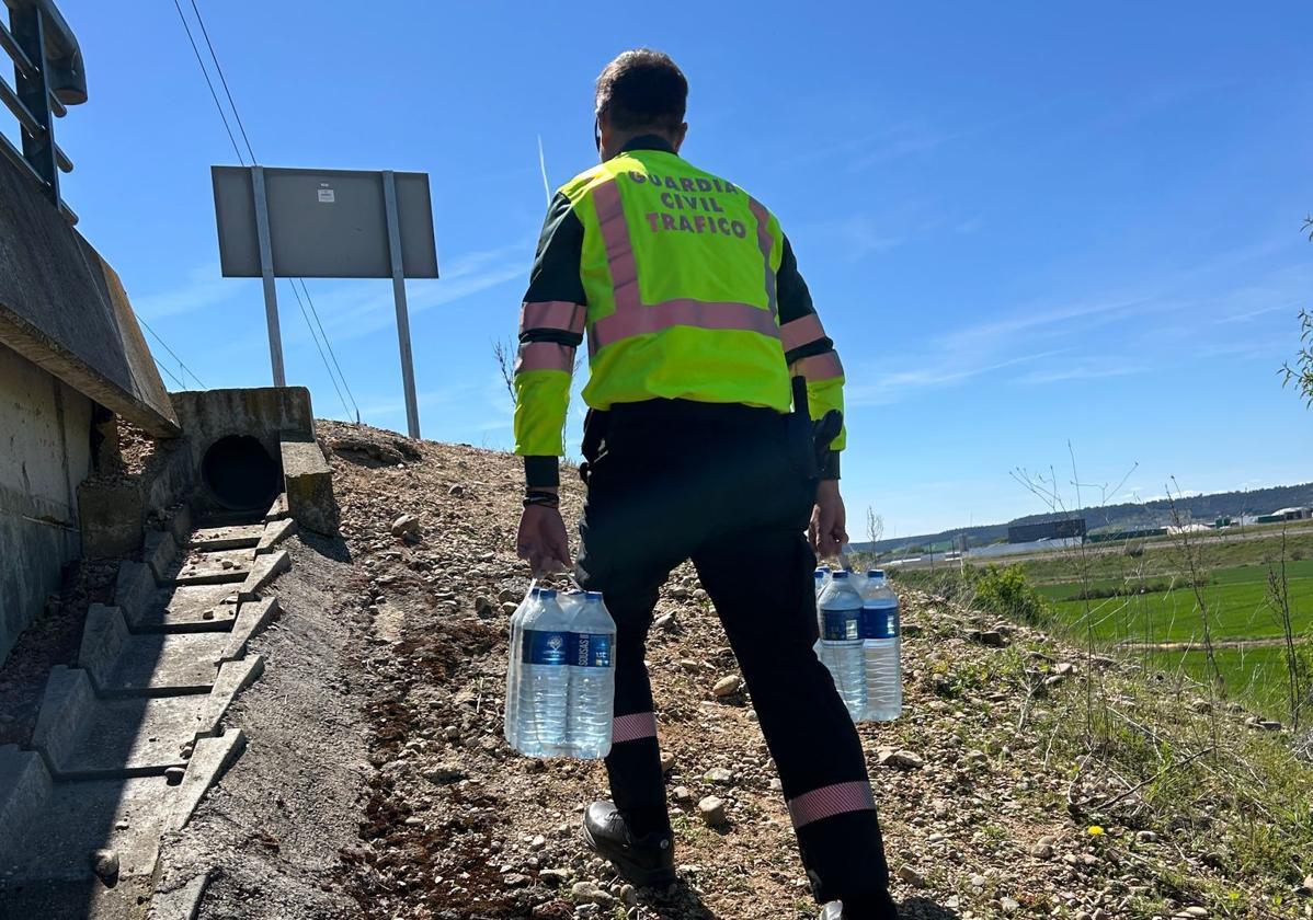 Un guardia civil lleva las botellas de agua a los pasajeros del tren.