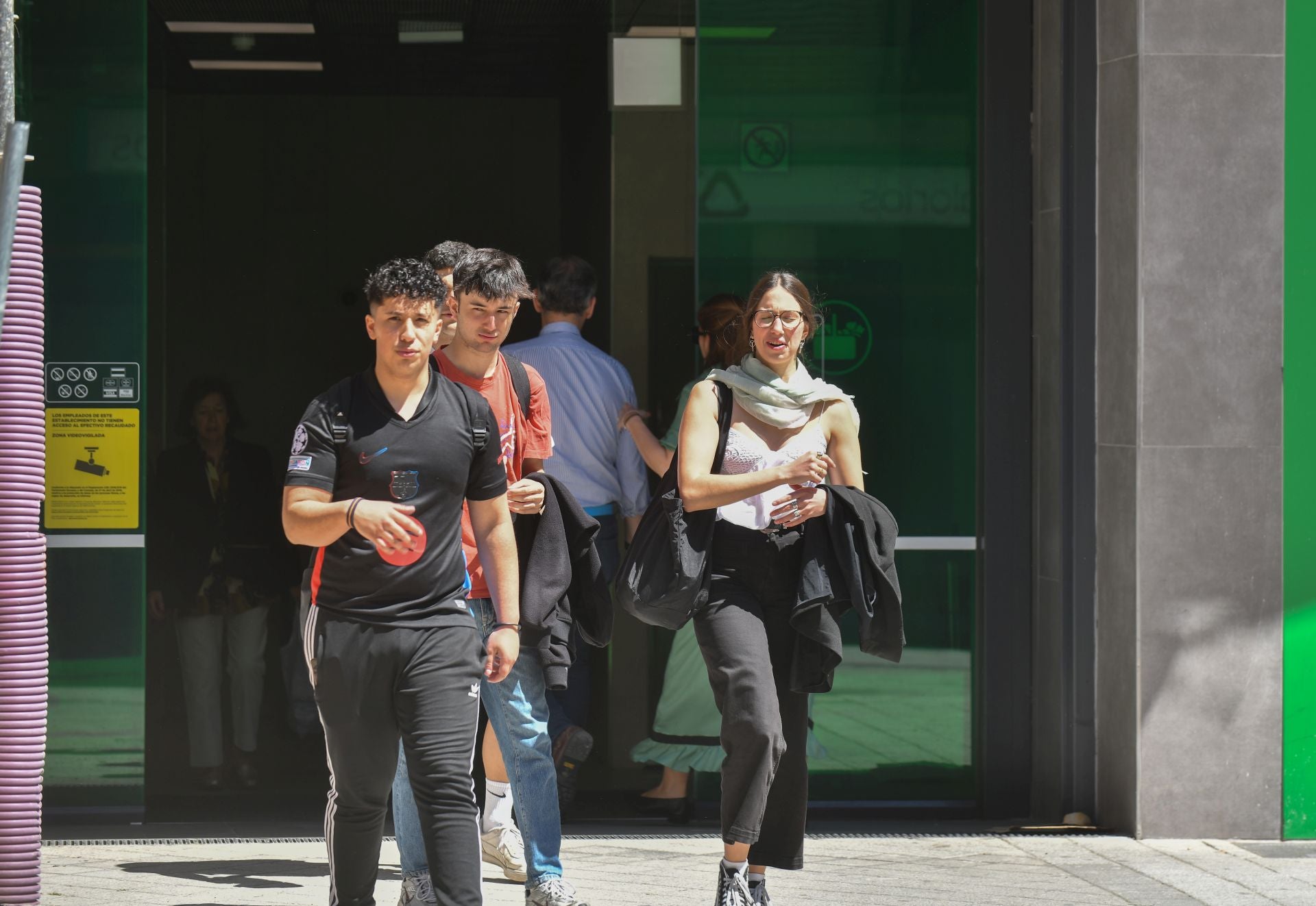 Varios jóvenes salen de un supermercado sin suministro eléctrico en la calle Alonso Pesquera.