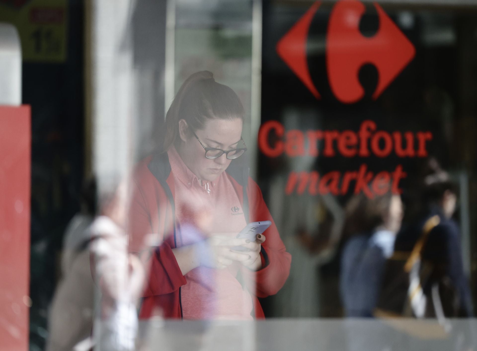 Una dependienta del Carrefour Market de la calle Santiago consulta su teléfono móvil.