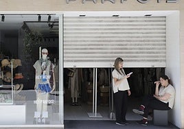 Empleadas de Parfois custodian este lunes el acceso al interior de la tienda durante el apagón, que dejó la verja a medio bajar.