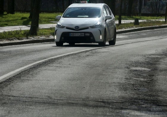 Un taxi circula por una carretera en mal estado en Segovia capital.