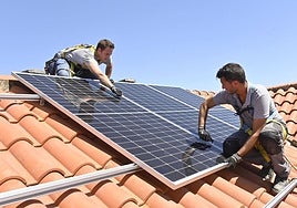 Dos instaladores colocan paneles solares en un tejado.