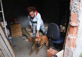 Ismael Trinidad sujeta a su perro dentro del habitáculo okupado en el que vive con su pareja Yenni Garro en el número 23 de la calle Domingo Martínez.