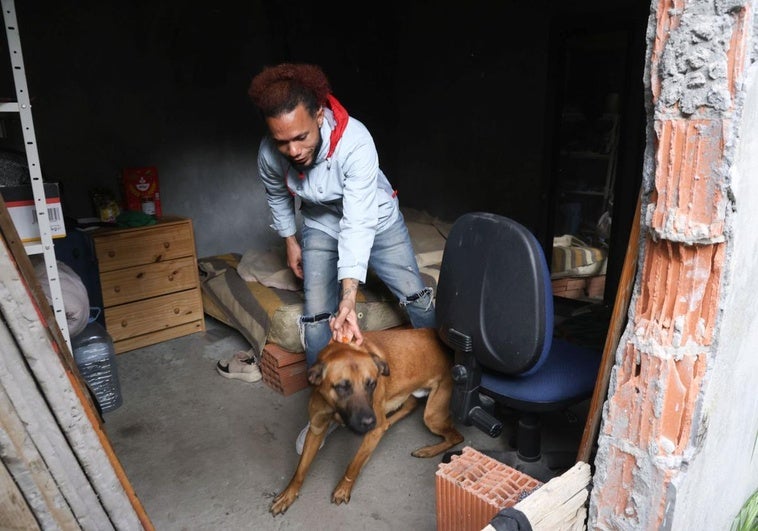 Ismael Trinidad sujeta a su perro dentro del habitáculo okupado en el que vive con su pareja Yenni Garro en el número 23 de la calle Domingo Martínez.