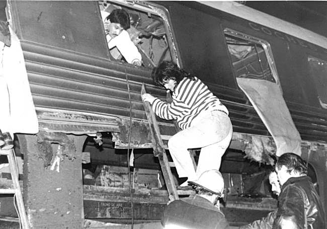 Una pasajera que salió ilesa de la colisión abandona por la ventanilla el vagón.