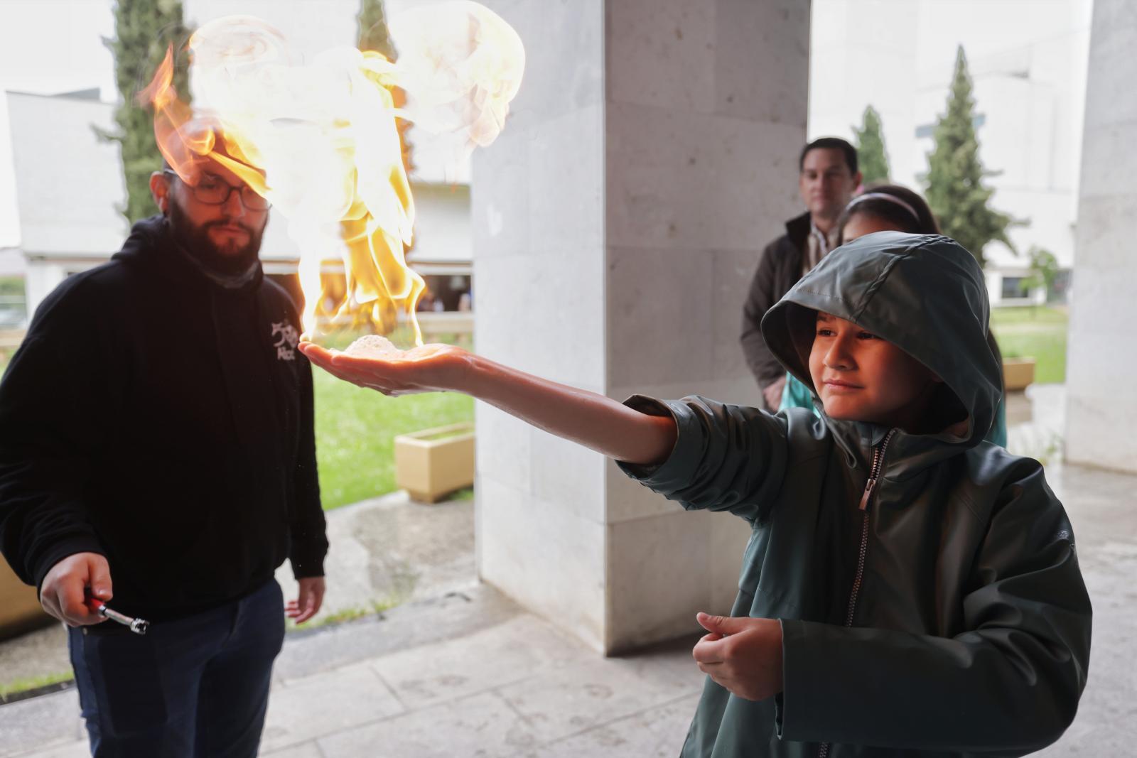 Un niño mantiene una llama en su mano durante la Feria de Ciencia Sostenible