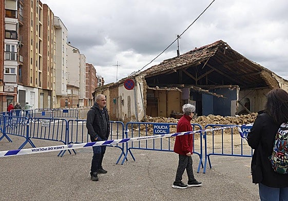 Un grupo de viandantes contempla la vivienda derruida.