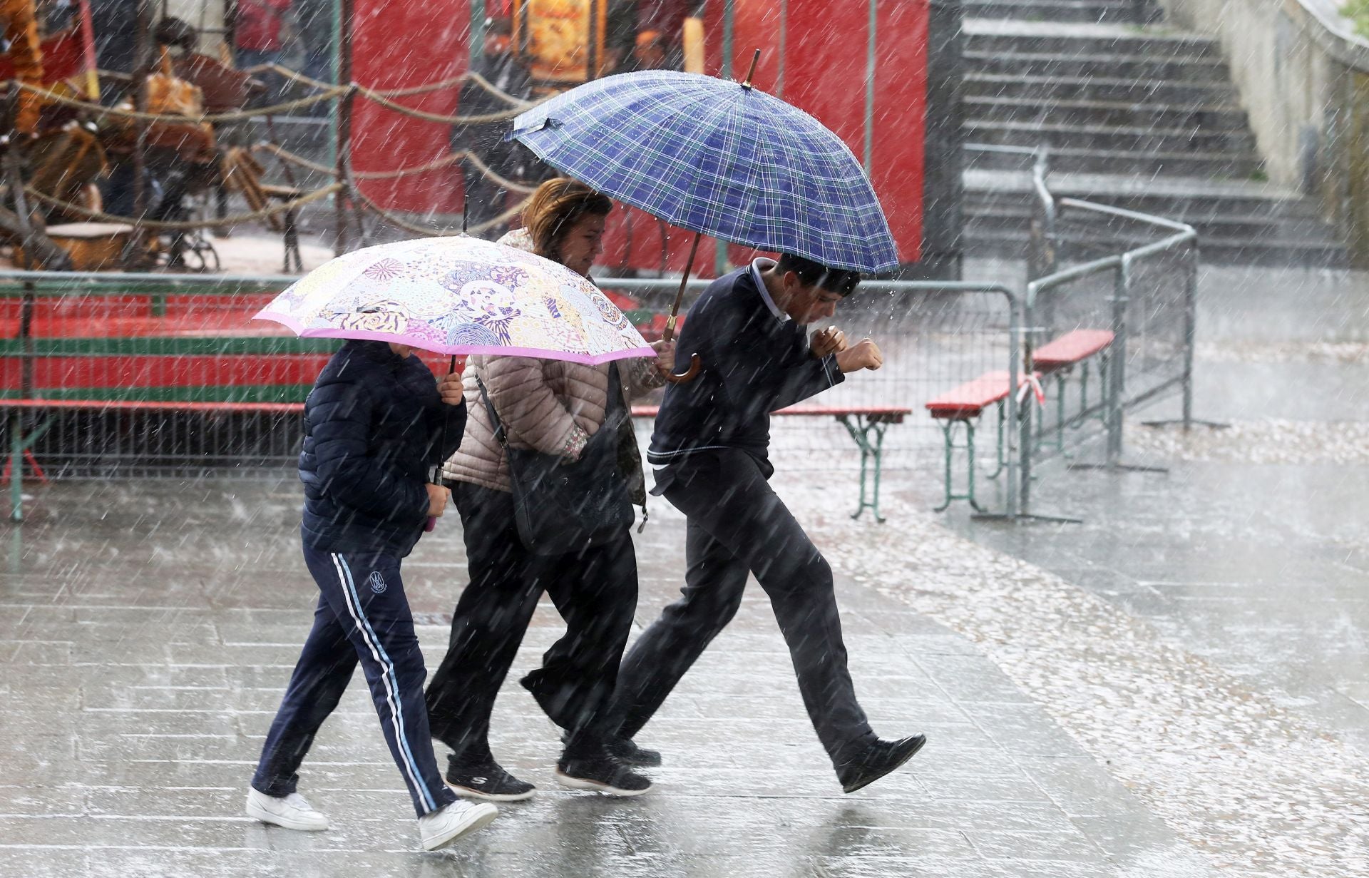 Tres personas intentan protegerse de la lluvia caída este miércoles en Segovia capital.