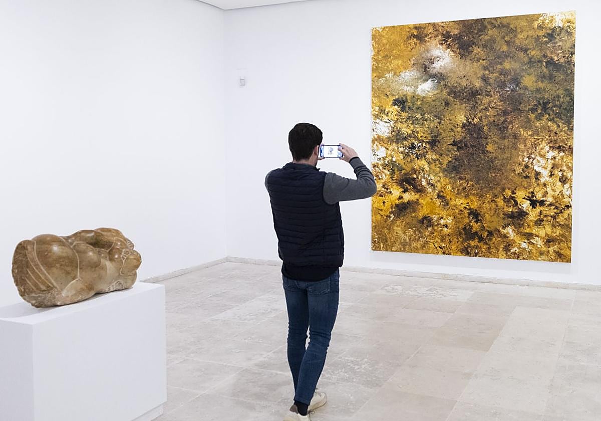 Un visitante, ante una escultura de Baltasar Lobo y el lienzo 'El dorado', de Carlos León.