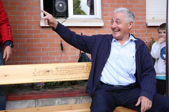 José Luis Cuadrado, sonriente en el banco con una inscripción grabada en homenaje a su trabajo durante 37 años en el centro.