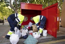 Daniel Oliveros y Juan Borja, trabajadores de Ecocircular, sacan los productos textiles arrojados en uno de los contenedores repartidos por la ciudad.