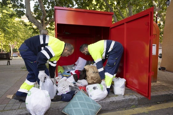 Daniel Oliveros y Juan Borja, trabajadores de Ecocircular, sacan los productos textiles arrojados en uno de los contenedores repartidos por la ciudad.
