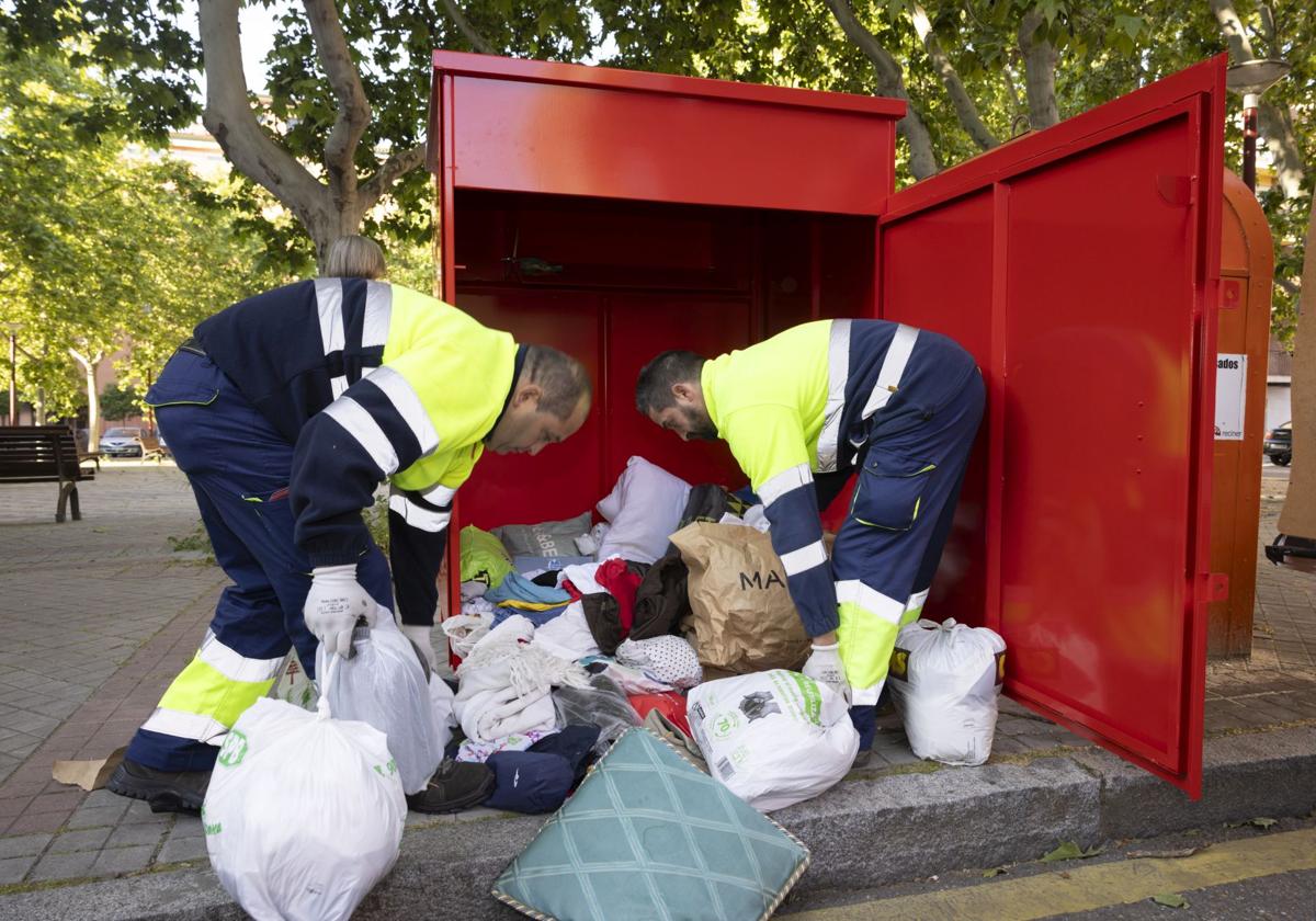 Daniel Oliveros y Juan Borja, trabajadores de Ecocircular, sacan los productos textiles arrojados en uno de los contenedores repartidos por la ciudad.