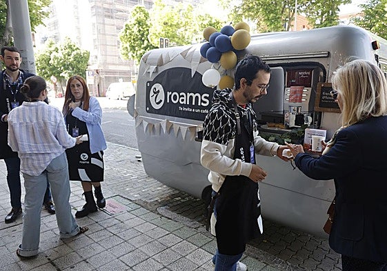 Varias personas se detienen a conocer los servicios de Roams y a tomar un café.