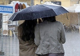 Dos personas se protegen de la lluvia con un paraguas en Segovia.