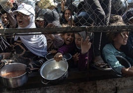 Palestinos se concentras frente a un comedor social para recibir alimentos.