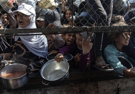 Palestinos se concentras frente a un comedor social para recibir alimentos.