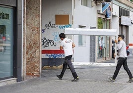 Dos trabajadores portan una ventana.