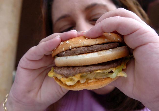 Una adolescente se dispone a comer una hamburguesa doble.