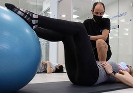 Un fisioterapeuta guía a una mujer en la tabla de ejercicios durante una sesión en un centro de Segovia.