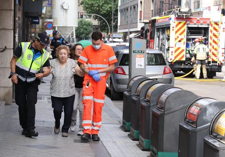 Los servicios de emergencia ayudan a una mujer a salir de la zona del incendio.