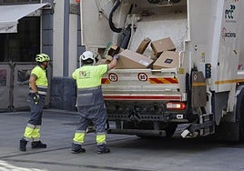 Trabajadores de Palencia Deslumbra recogen basuras de los comercios de la Calle Mayor.