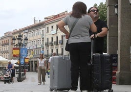 Una pareja de turistas, en el centro de Segovia con decoración de las fiestas al fondo.