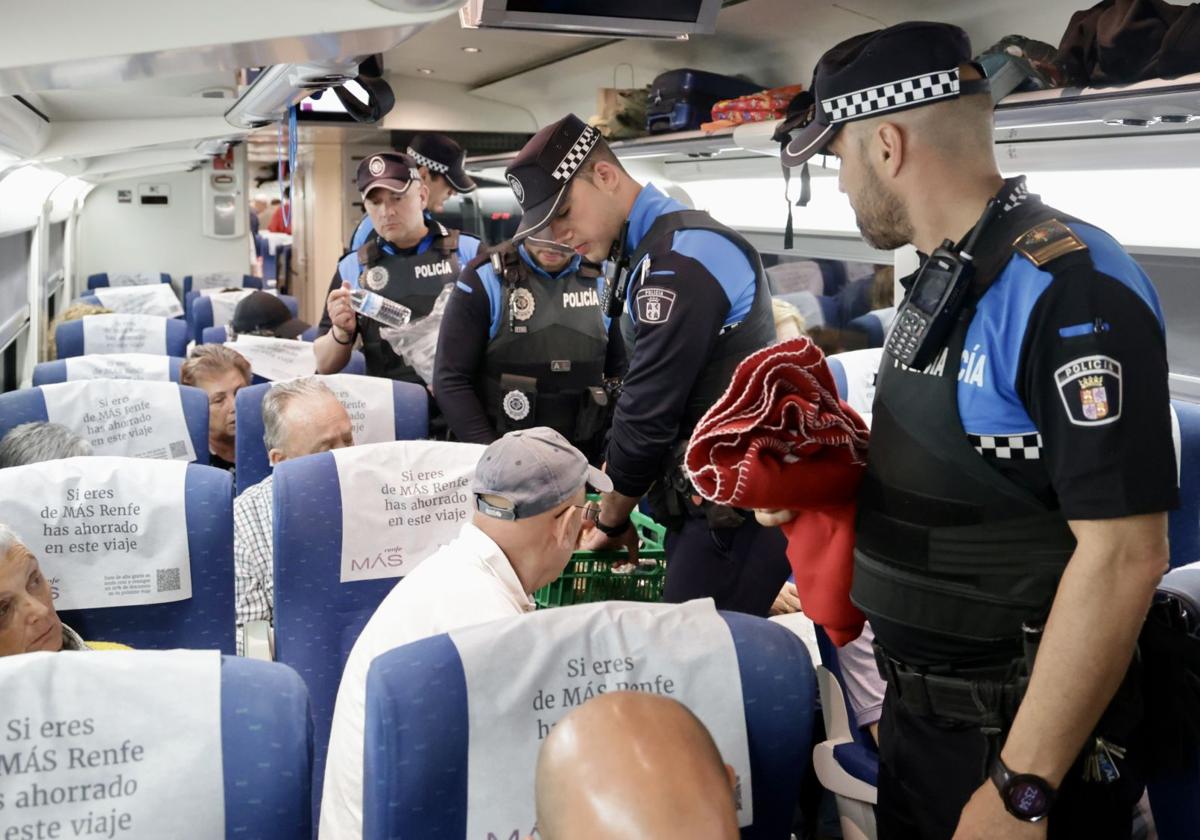 Agentes de la Policía Local de Valladolid distribuyen agua, alimentos y mantas entre los pasajeros de un tren parado en la estación Campo Grande como consecuencia del apagón.