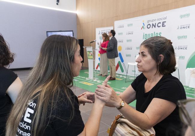 Una personas con sordoceguera y una mediadora se comunican durante la presentación de la campaña de concienciación de la ONCE.
