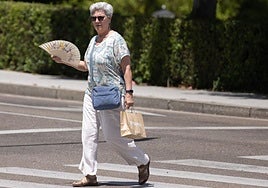 Una mujer cruza, abanico en mano, un paso de peatones en el centro de Valladolid.