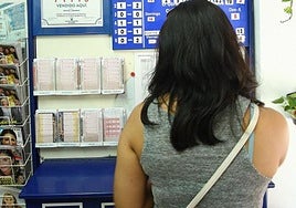 Una mujer elige uno de los boletos para participar en los sorteos de loterías.