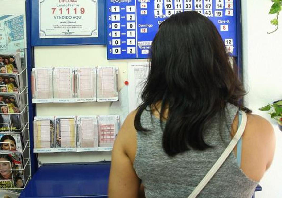 Una mujer elige uno de los boletos para participar en los sorteos de loterías.