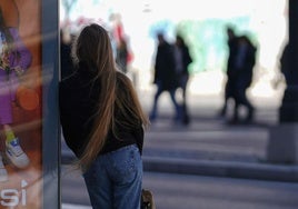 Una adolescente espera al autobús en una parada de transporte.