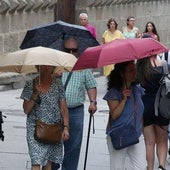 Varias personas se protegen de la lluvia con paraguas en Segovia.